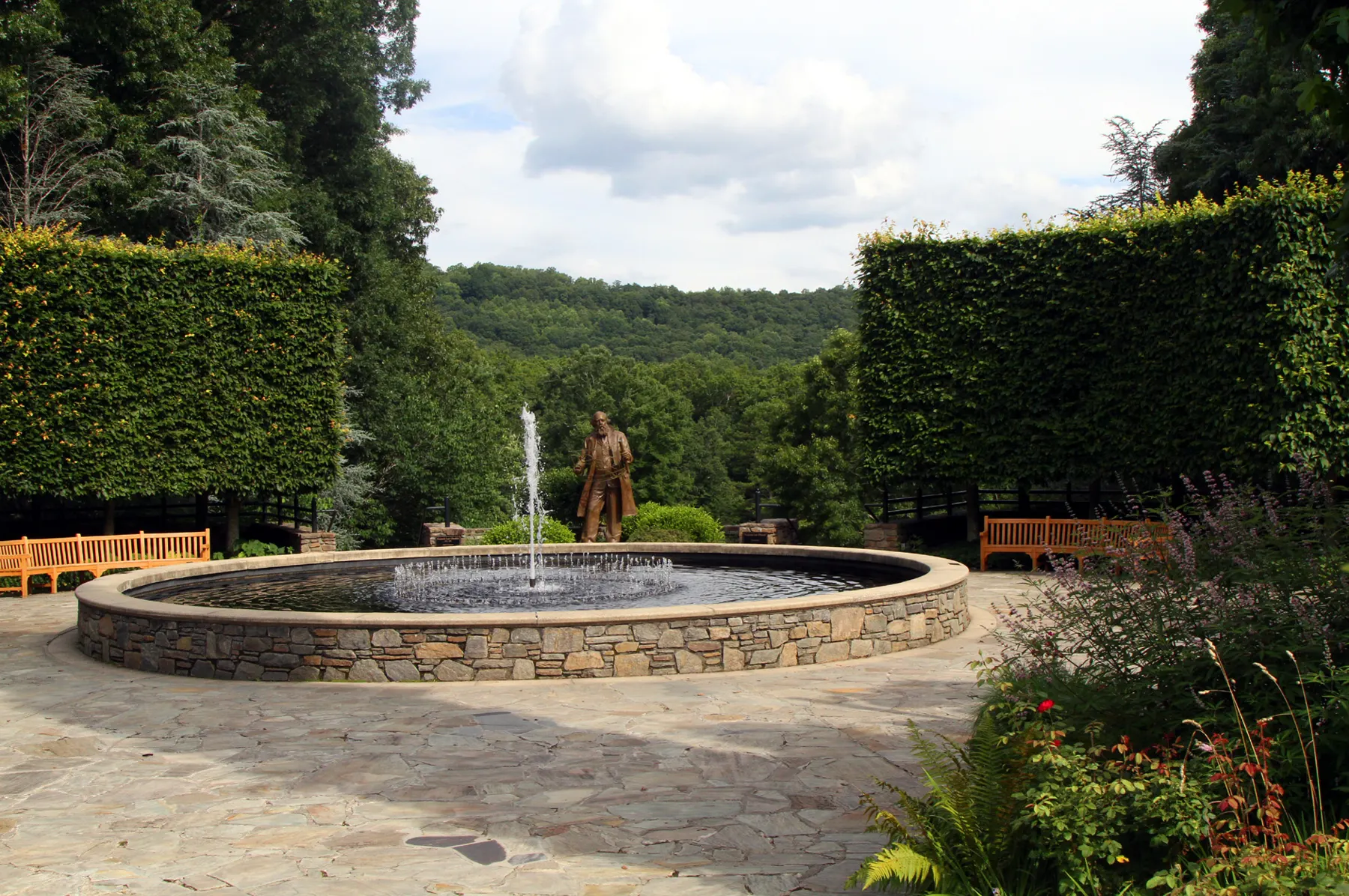 Paved paths around a round stone fountain in the NC Arboretum's gardens