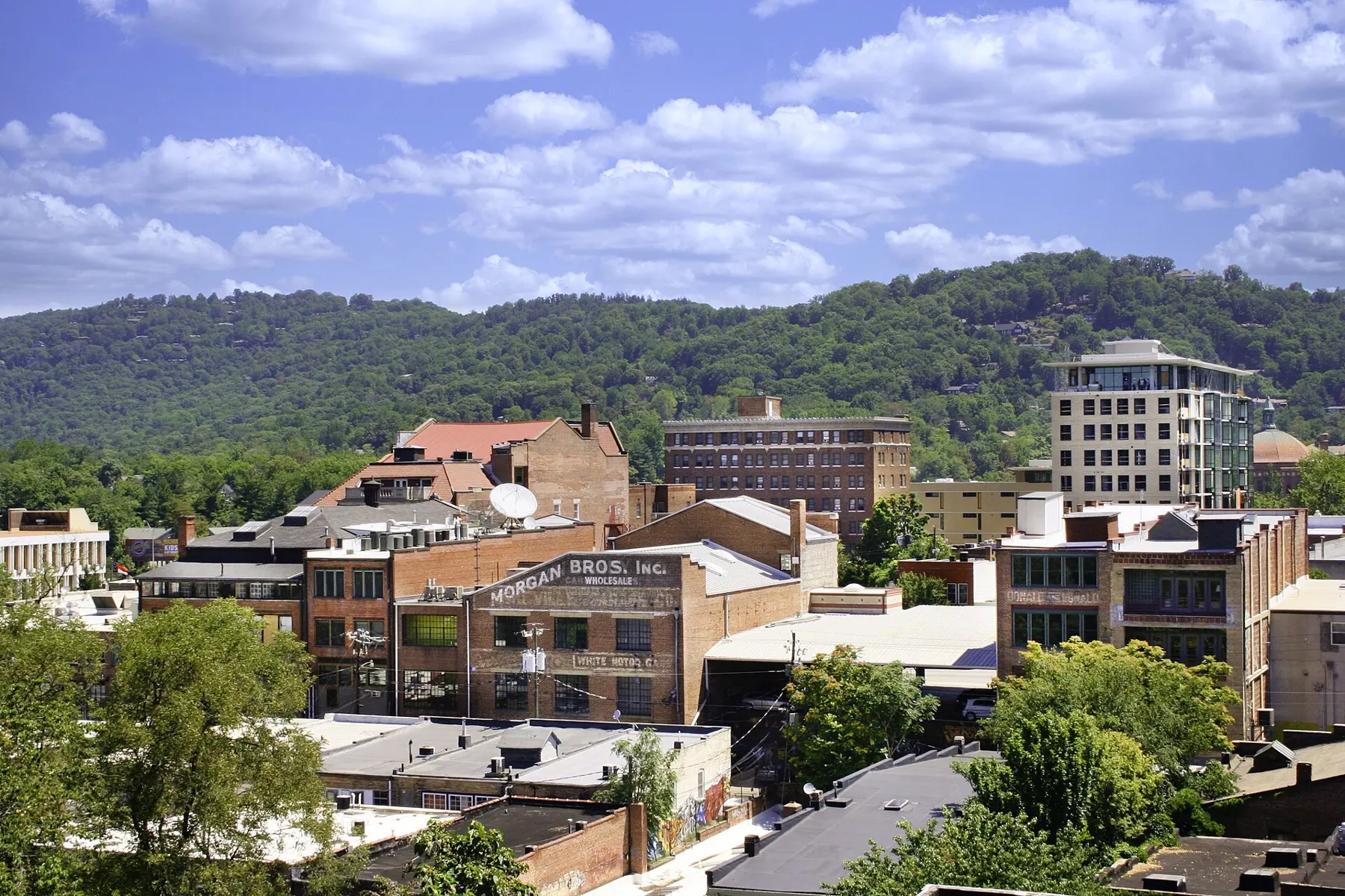 Downtown Asheville's brick buildings and rooftops with green mountains behind